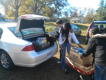 Image of volunteers unloading food supplies from a car trunk