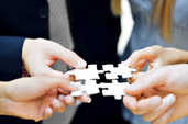 Image of business people holding interconnecting puzzle pieces